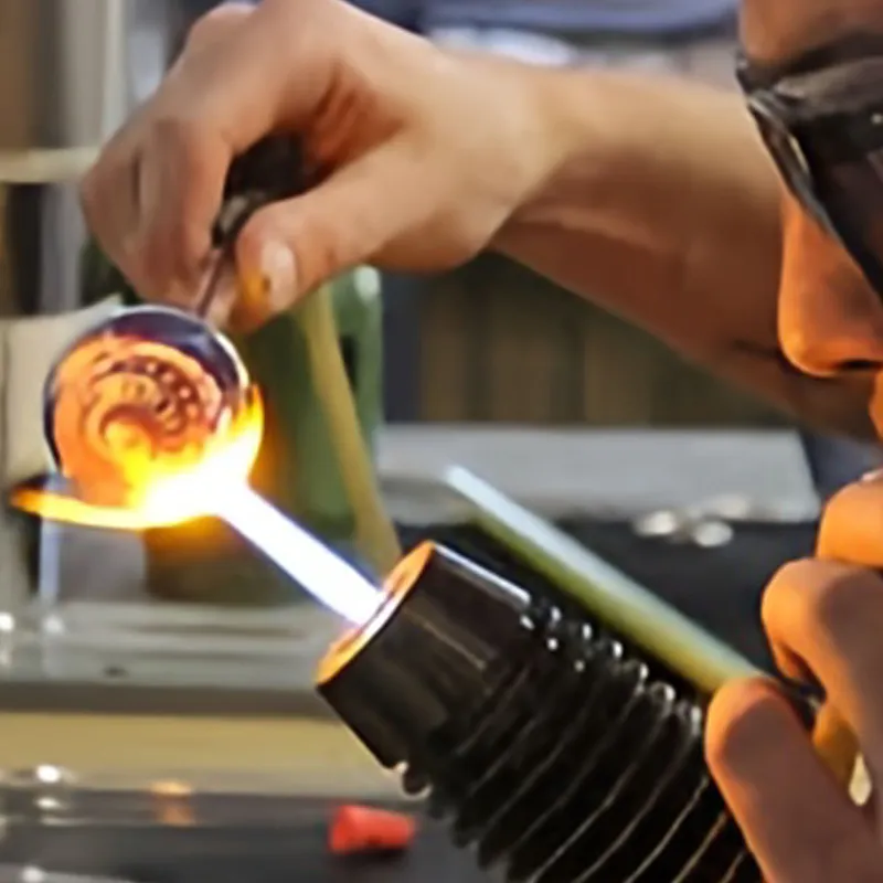 Glassblower shaping molten glass with a torch
